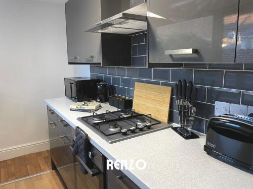 a kitchen with a stove top oven next to a counter at Spacious 2 Bedroom home in Lincoln by Renzo, Victorian Townhouse, Flexible Check-In! in Lincolnshire