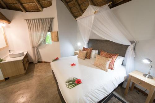 ein Schlafzimmer mit einem weißen Bett mit Blumen darauf in der Unterkunft Sefapane Lodge and Safaris in Phalaborwa