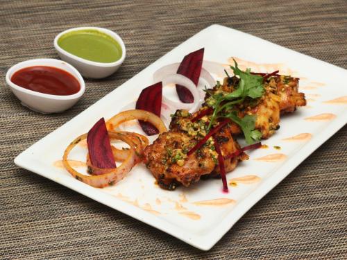 a plate of food with meat and onion rings at The Grand Orion - Kailash Colony in New Delhi