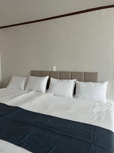 a large bed with white sheets and pillows at Bricks Stay Jeju City & Aiport in Jeju