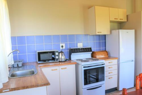 a kitchen with a white stove top oven next to a sink at Malolotja Log Cabins in Mbabane