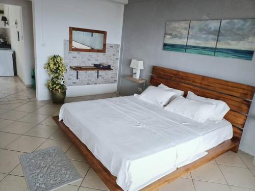 a bedroom with a large white bed with a wooden headboard at Surf house holidays in Baie du Cap