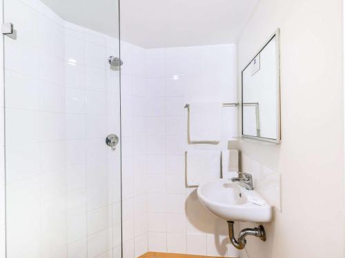 a white bathroom with a sink and a shower at ibis budget Sydney Airport in Sydney
