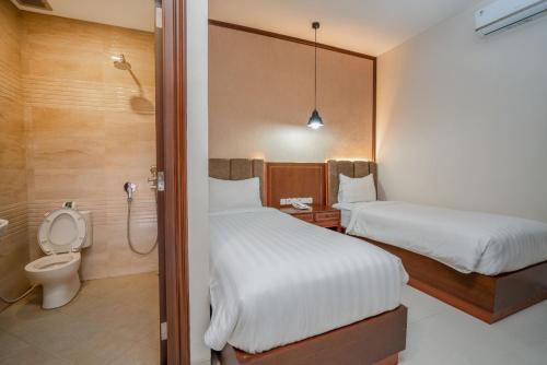 a hotel room with two beds and a shower at Hadipriyanto Homestay in Banyumas