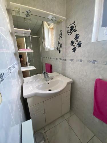 une salle de bain blanche avec un lavabo et un miroir dans l'établissement Hôtel restaurant l'escale chez mimi, à Bioule