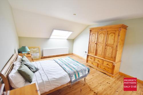 um quarto com uma cama e um armário de madeira em Sheelagh's Kitchen em Ballyferriter