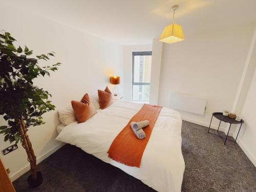 a bedroom with a white bed with an orange blanket at 2 Bed Apartment Sleeps 6 Modern Secure Parking + Lift in Newcastle upon Tyne