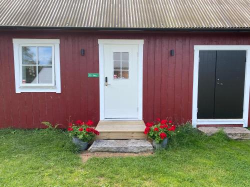 a red house with a white door and some flowers at Skog Fegen nära Ullared in Fegen