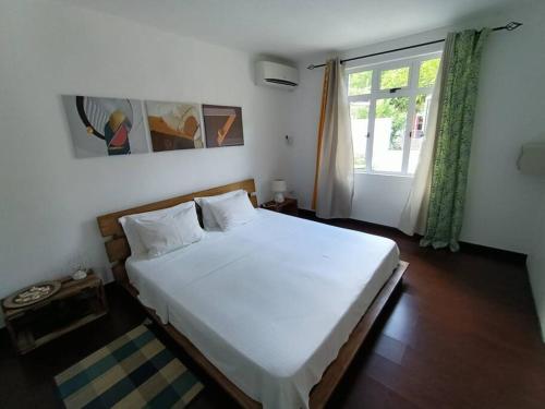 a bedroom with a large white bed and a window at Surf house holidays in Baie du Cap