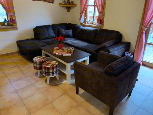 a living room with a black leather couch and a table at Chalupa na Leskové in Velké Karlovice