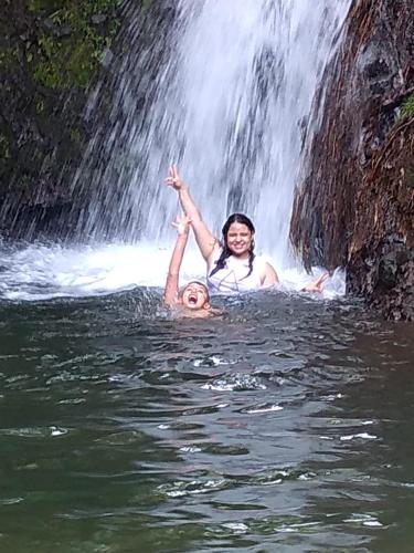 two people in the water in front of a waterfall at Alojamiento EL GITANO in Filandia