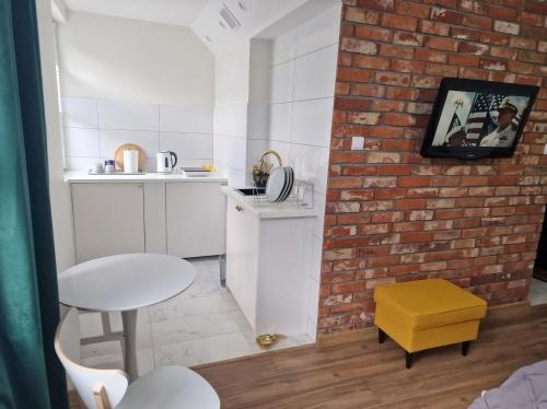 eine Küche mit einer Ziegelwand, einem Tisch und einem gelben Stuhl in der Unterkunft Kawalerka na pierwszym piętrze in Malbork