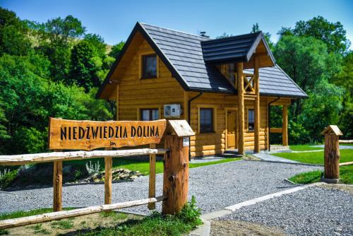 un panneau en bois devant une cabane en rondins dans l'établissement Niedźwiedzia Dolina, à Przybyszów