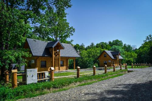 une cabane en bois avec une clôture à côté dans l'établissement Niedźwiedzia Dolina, à Przybyszów