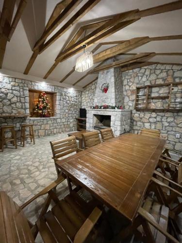 Cosy cottage Andrej في Danilovgrad: غرفة طعام مع طاولة خشبية ومدفأة حجرية