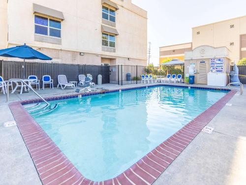 una gran piscina con sillas y sombrilla en Comfort Inn Hanford Lemoore, en Hanford