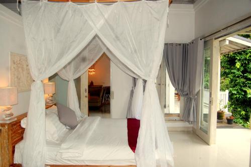 a bedroom with a canopy bed with white curtains at Balian Bliss Retreat Bungalow & Villas in Balian