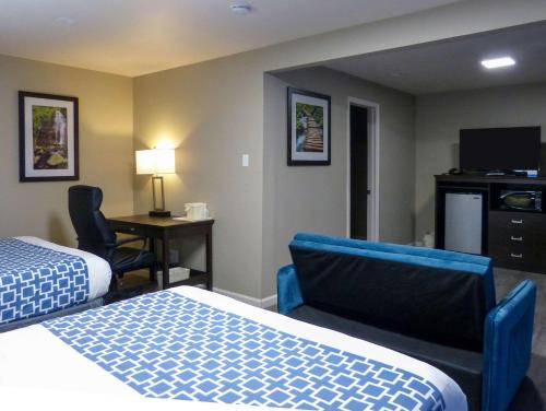 安大略的住宿－Rodeway Inn & Suites，酒店客房设有两张床、一张桌子和一台电视。