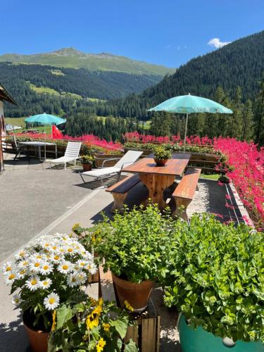 a patio with flowers and a table and chairs at BnB Guesthouse Lusi in Frauenkirch