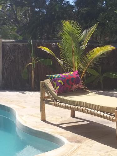 a bench with pillows next to a swimming pool at Mpole Bungalows in Michamvi