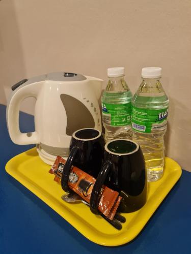 a tea kettle and two bottles of water on a yellow tray at Hotel Bestari in Kuala Lipis