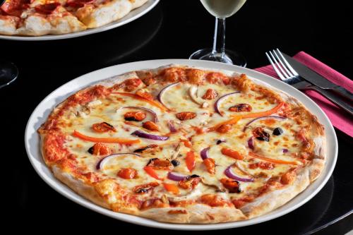 a pizza on a white plate on a table at New Continental Hotel; Sure Hotel Collection by Best Western in Plymouth