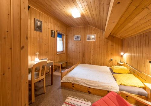 a bedroom with two beds and a desk and a table at B&B Pranzaira in Vicosoprano