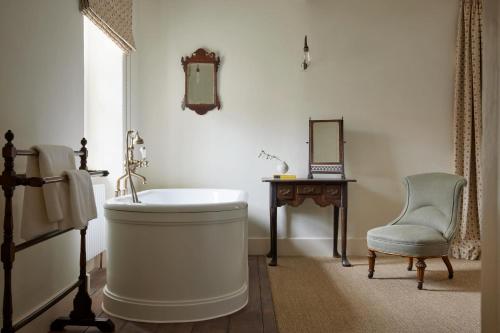 a bathroom with a tub and a chair and a desk at The Bradley Hare in Maiden Bradley