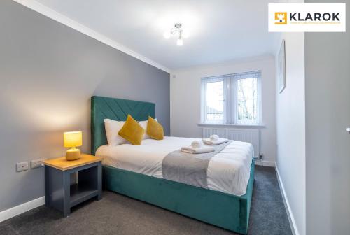 a bedroom with a bed with a green headboard and a table at LONG STAYS 30pct OFF - Spacious 4Bed - Sports Channels - Parking By Klarok Short Lets & Serviced Accommodation in Peterborough
