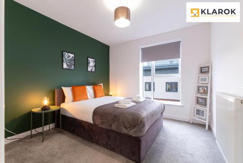 a bedroom with a large bed and a green wall at LONG STAYS 30pct OFF - Superb Central 2Bed Apt with Parking By Klarok Short Lets & Serviced Accommodation in Peterborough