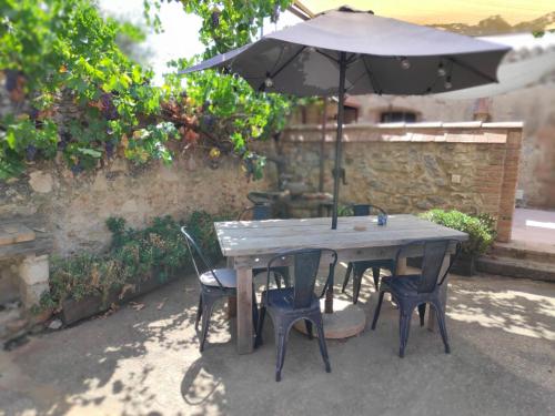 a wooden table with chairs and an umbrella at Mas Del Llop Blanc - Dog friendly Hostal Rural - B&B in Sobrestany