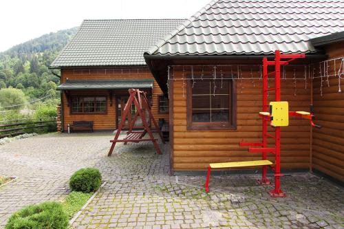 a wooden cabin with a red ladder and a playground at Шале На бе́резі in Kvasy