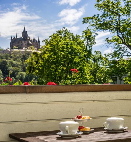 a table with two cups and plates of food on a balcony at Boutiquehotel Schloßpalais in Wernigerode