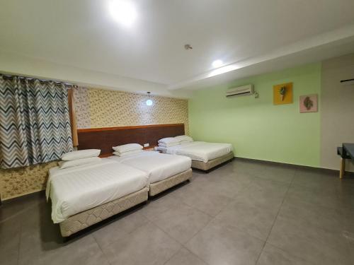 a room with two beds and a television in it at Hotel Bestari in Kuala Lipis