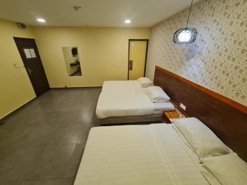 a hotel room with two beds and a hallway at Hotel Bestari in Kuala Lipis