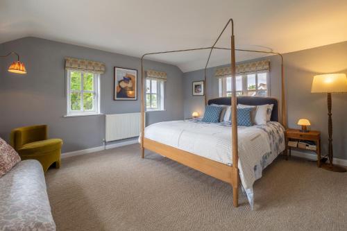 a bedroom with a canopy bed and a chair at Foxhole Cottage in Stowmarket