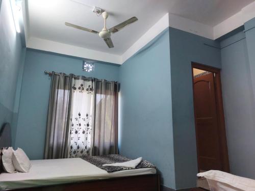 a bedroom with a ceiling fan and blue walls at Hotel Quality in Kakarvitta