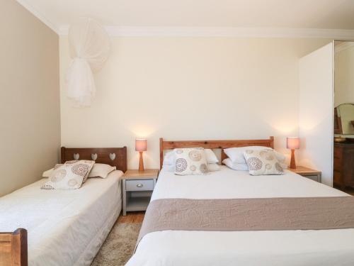 a bedroom with two beds with white sheets and pillows at Heselwood in Lyme Regis