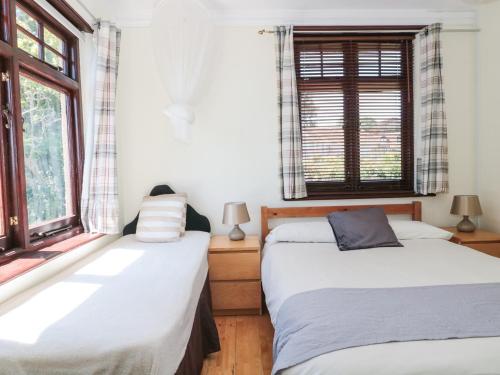 two beds in a room with two windows at Heselwood in Lyme Regis
