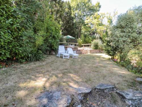 two white chairs sitting in a yard at Heselwood in Lyme Regis