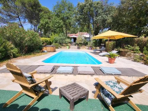 a pool with two chairs and a table and an umbrella at Le Phoenix de Sainte Victoire in Saint-Marc-Jaumegarde