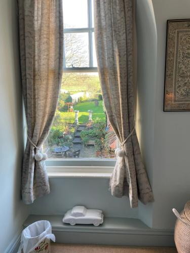 a window with curtains with a view of a garden at Ellesmere House in Castle Cary