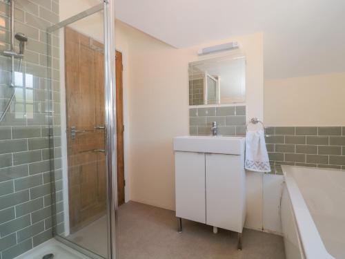 a bathroom with a shower and a sink and a mirror at The Coach House in Lyme Regis