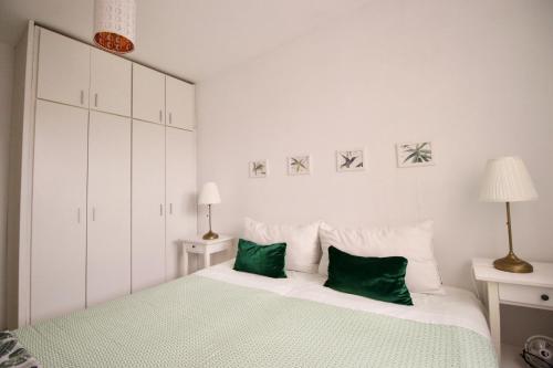 a white bedroom with a large bed with green pillows at Sweet Home Apartaments in El Médano