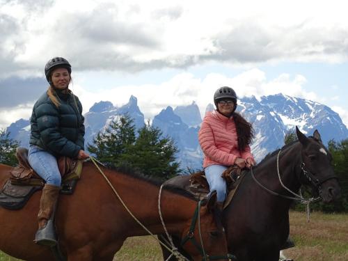 two people on horses with mountains in the background at Departamentos 8va Maravilla in Torres del Paine