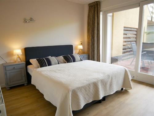 een slaapkamer met een bed met een witte deken en een raam bij Wijde Blick XL aan Zee in Callantsoog