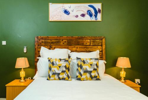 1 dormitorio con 1 cama con paredes verdes y 2 lámparas en Birdville BNB Guest House, en Gaborone