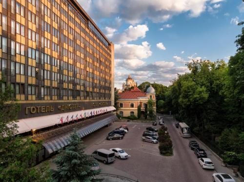 um grande edifício com carros estacionados num parque de estacionamento em Premier Hotel Dnister em Lviv