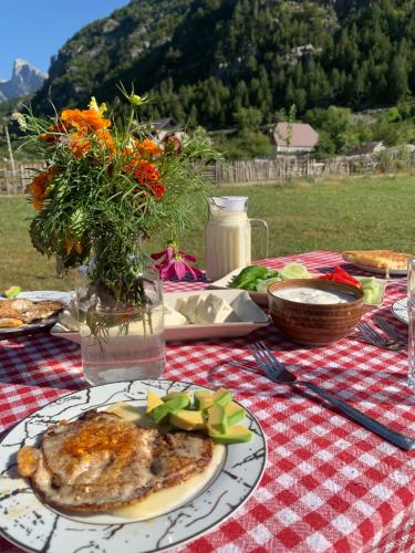 una mesa de picnic con un plato de comida y flores en Te Sofra, en Shkodër