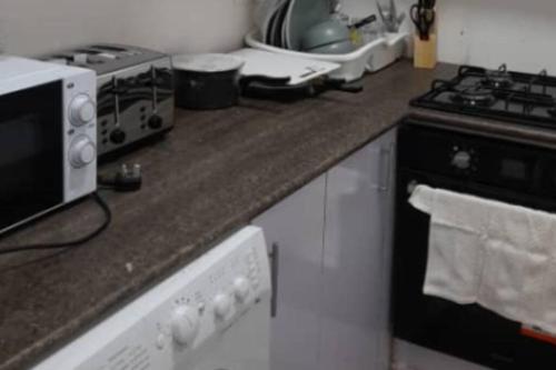 a kitchen counter with a stove and a microwave at Bambino Guest House in Brikama